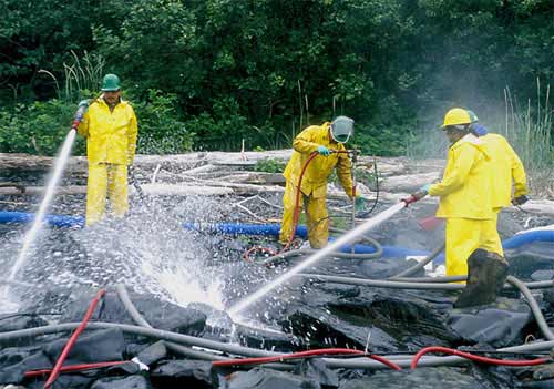 Workers shown cleaning oil from the shore after the Exxon Valdez oil spill
