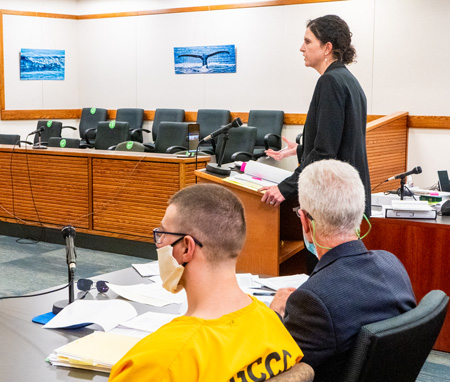 Palmer District Attorney Melissa Wininger-Howard stands in a courtroom with rows of empty chairs in the background. Bradley Renfro sits next to his attorney Chris Provost in the foreground.